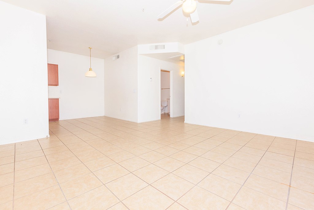 an empty living room with a tile floor and white walls