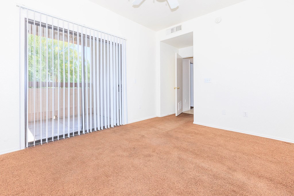 an empty living room with a window and a carpet