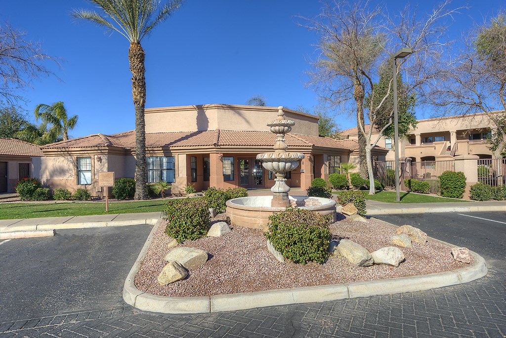a fountain in the center of a parking lot in front of a building