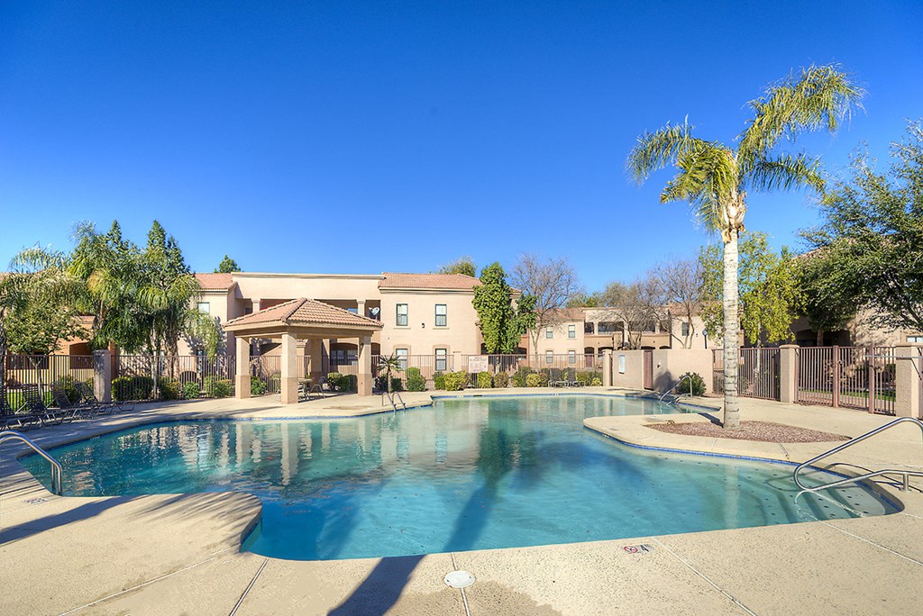 a swimming pool with palm trees and a building in the background