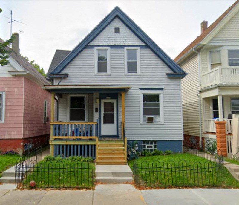 A blue house with a porch and a white door.