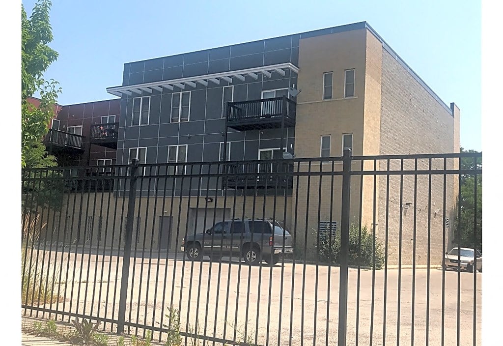 a car parked in front of a building behind a fence