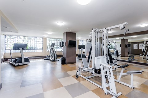 A gym with a variety of equipment including a treadmill, stationary bike, and weight machines.