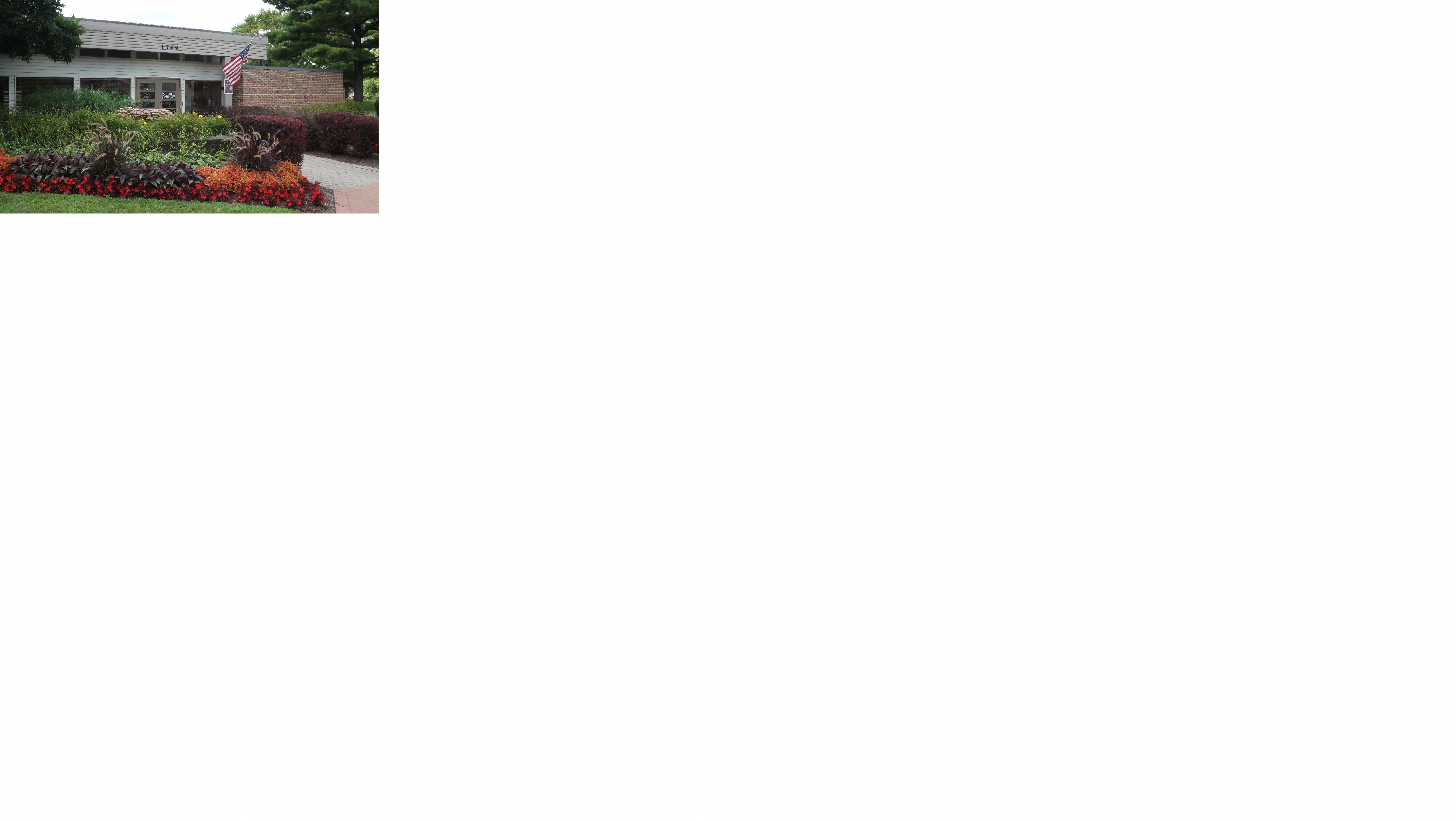 the front yard of a house with flowers and a sidewalk