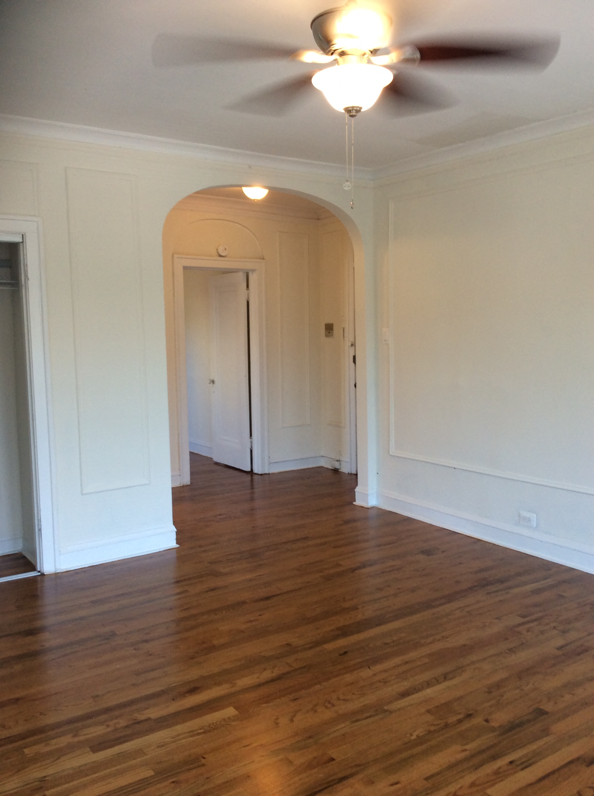 an empty living room with white walls and a ceiling fan