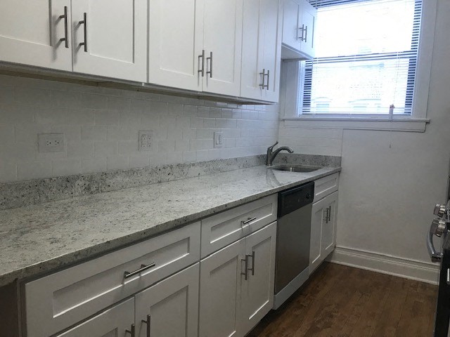 a kitchen with white cabinets and a sink and a window