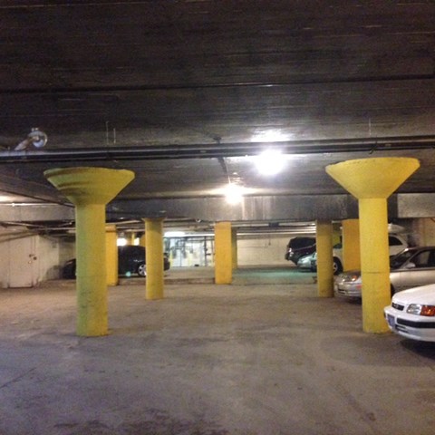 a parking garage with yellow pillars and cars