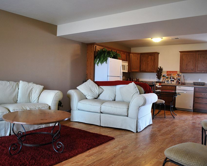 a living room and kitchen with white couches and a table
