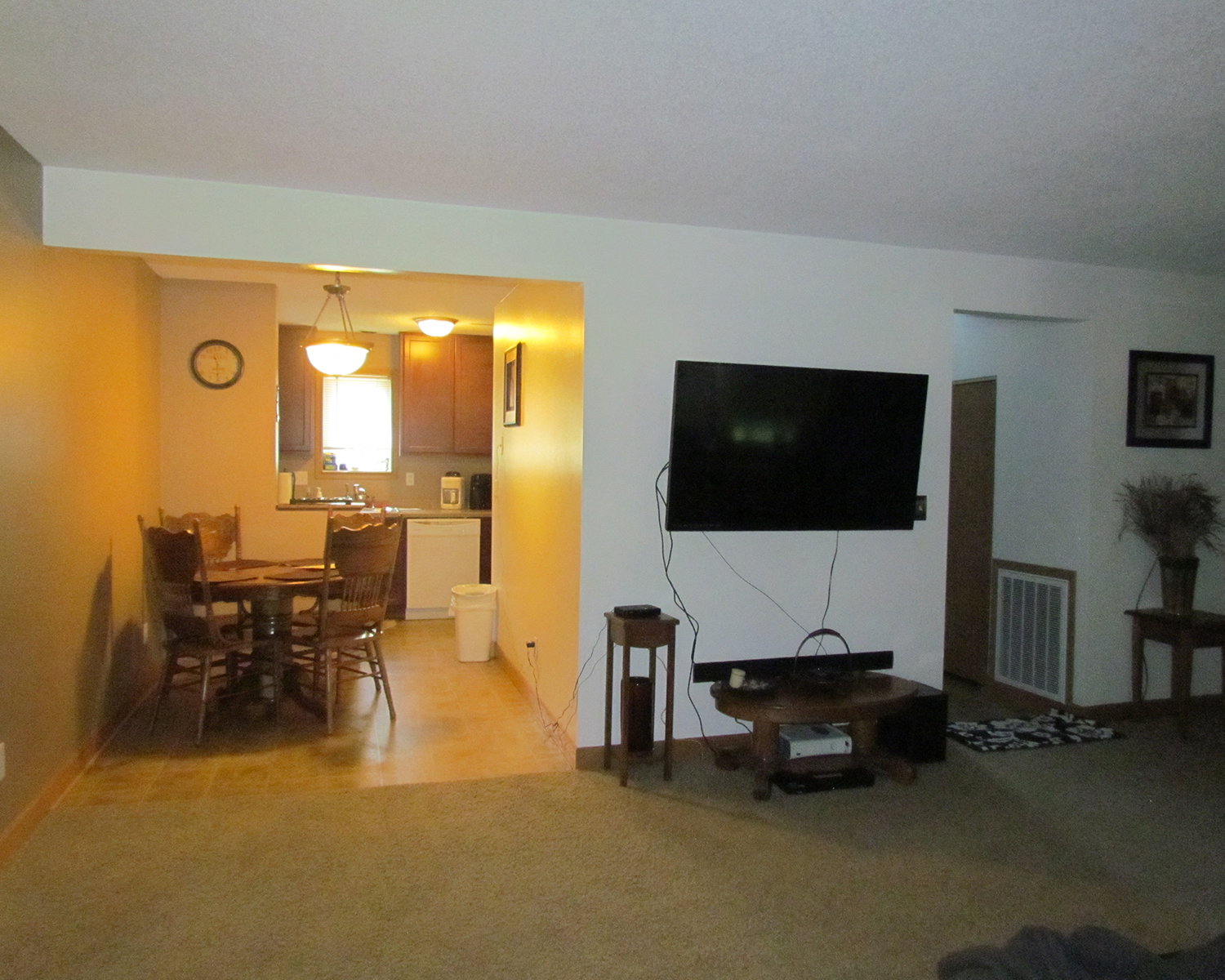 an empty living room with a tv and a dining room table