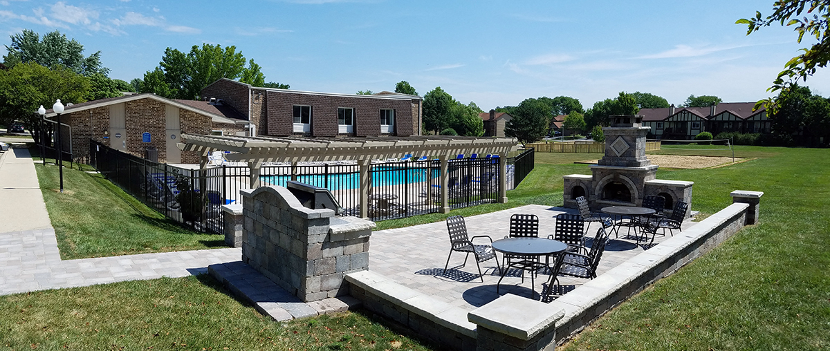 a patio with tables and chairs in front of a swimming pool