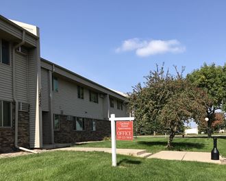 an apartment building with a red and white sign in the grass