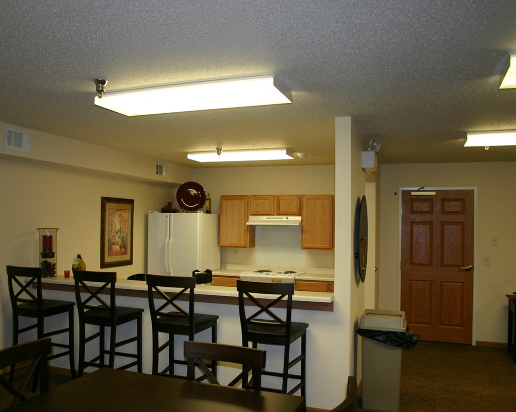 a kitchen with a bar and chairs and a refrigerator