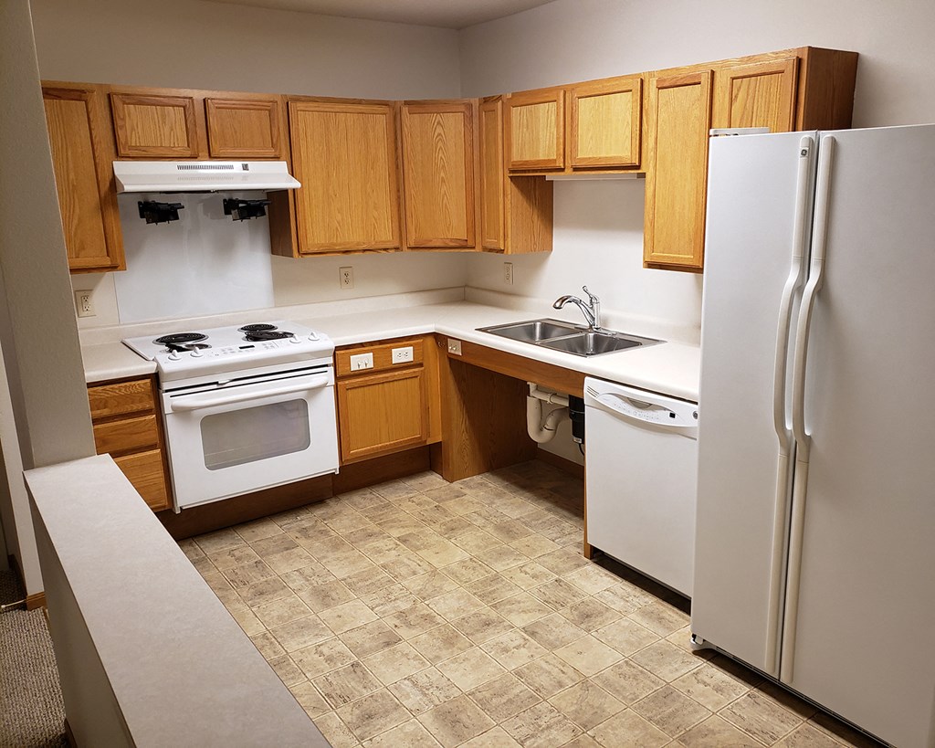 an empty kitchen with white appliances and wooden cabinets