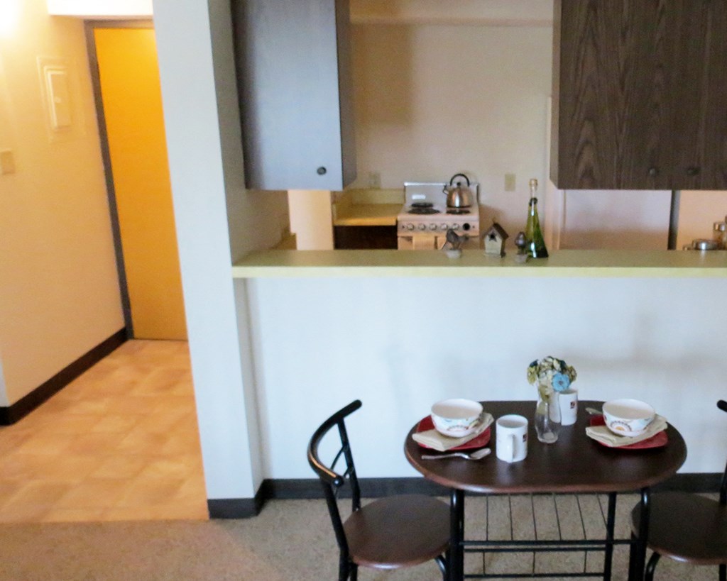 a small dining room with a table and chairs in front of a kitchen