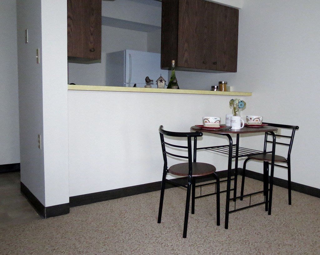 a small dining table with two chairs in front of a white wall