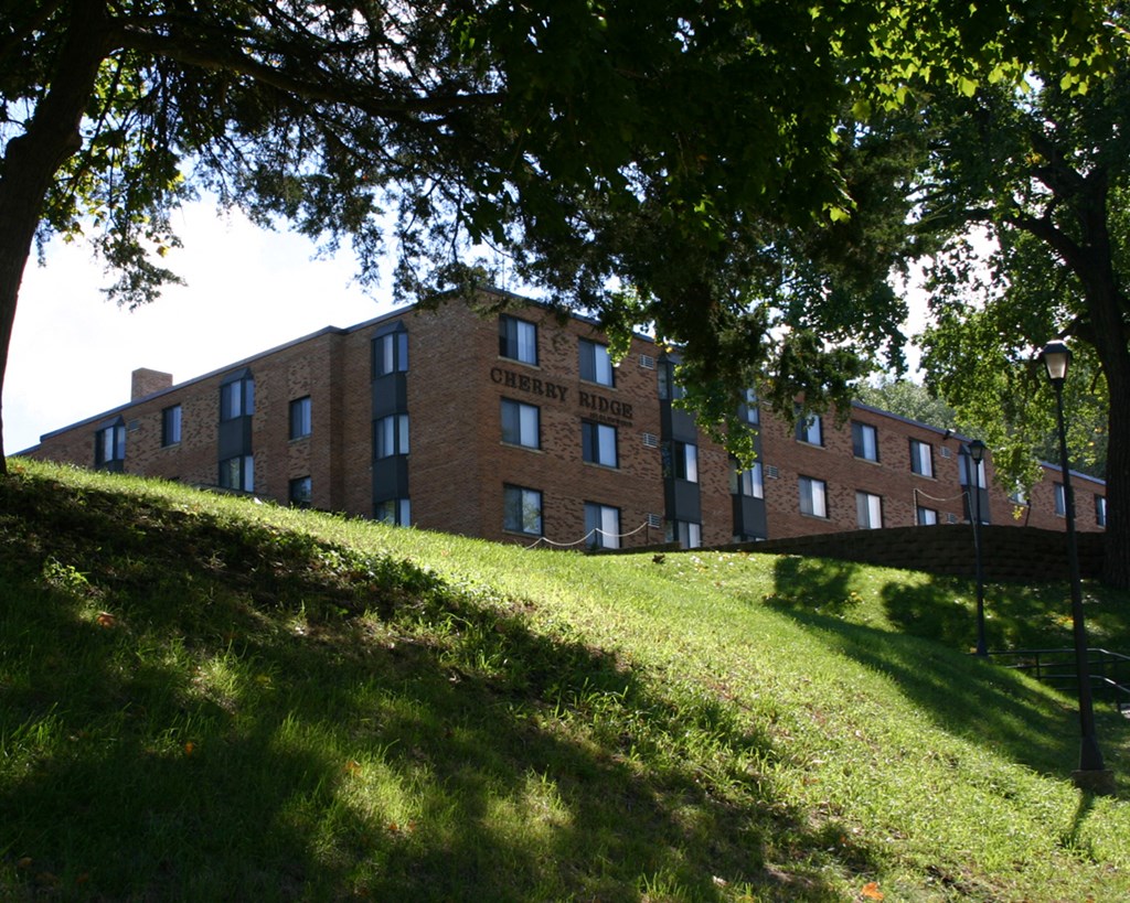 a large brick building on a hill with trees