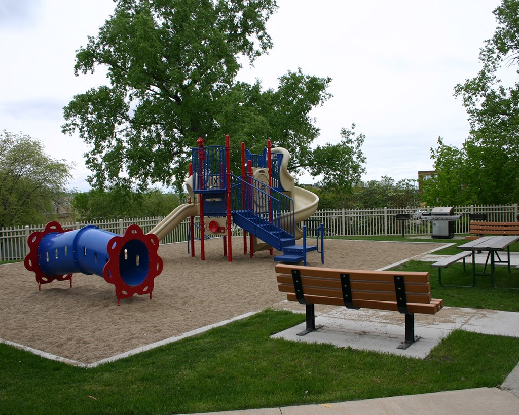 a playground with slides and benches in a park