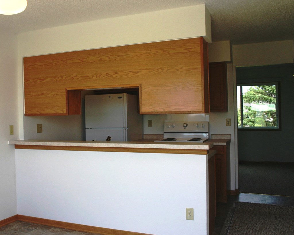 an empty kitchen with wooden cabinets and a white counter top