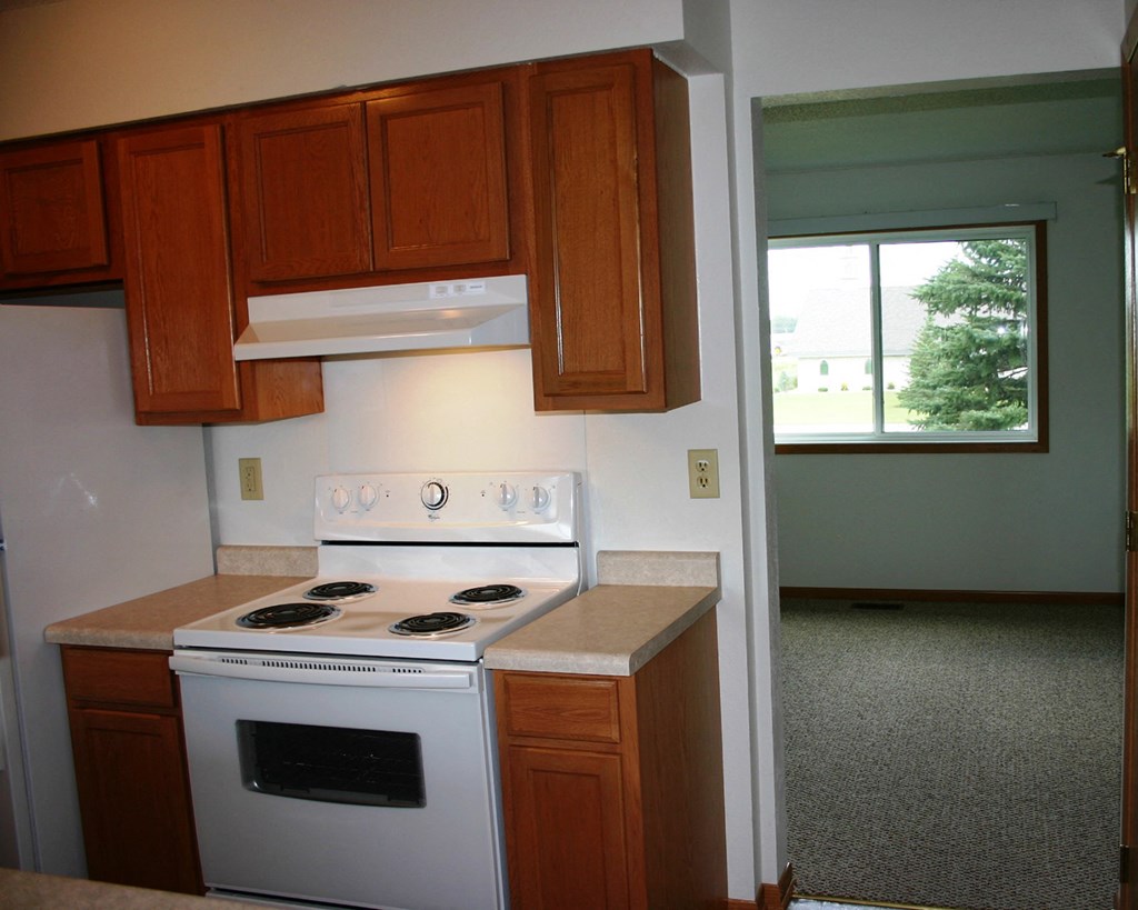 a kitchen with a stove and cabinets and a window