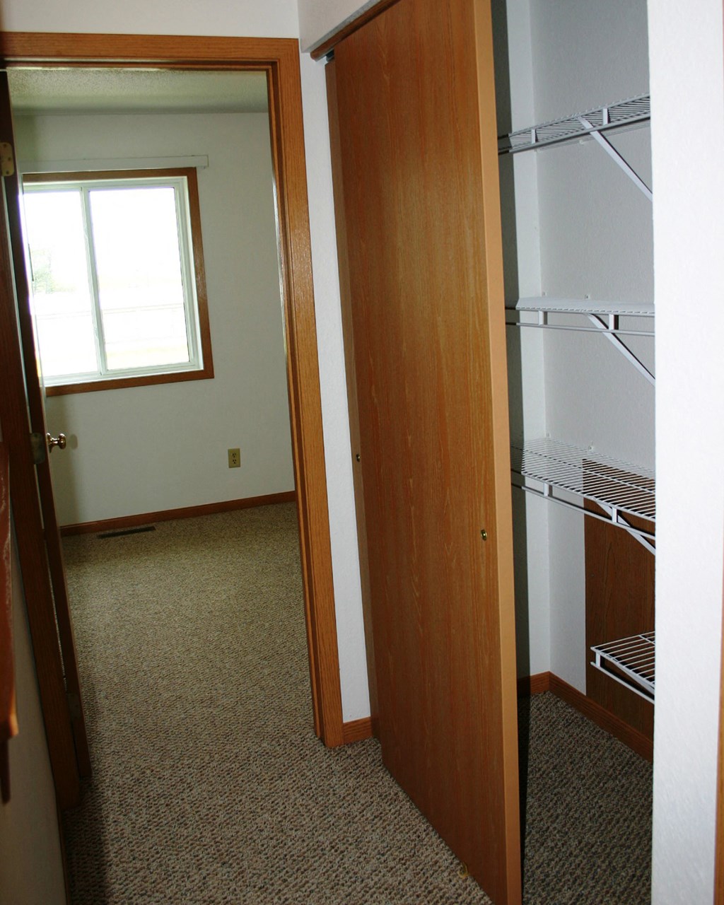 an empty closet in a room with a window and a door open to a closet
