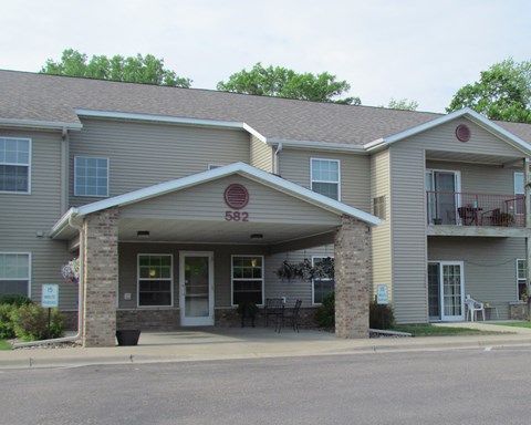 the front of a large apartment building with a porch and a table and chairs outside