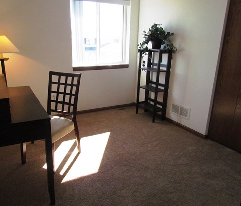 A room with a chair, a table, a window, and a potted plant.