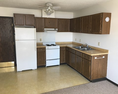 an empty kitchen with white appliances and wooden cabinets