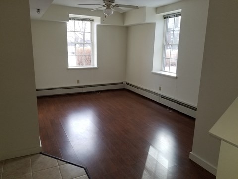 an empty living room with wood floors and a ceiling fan