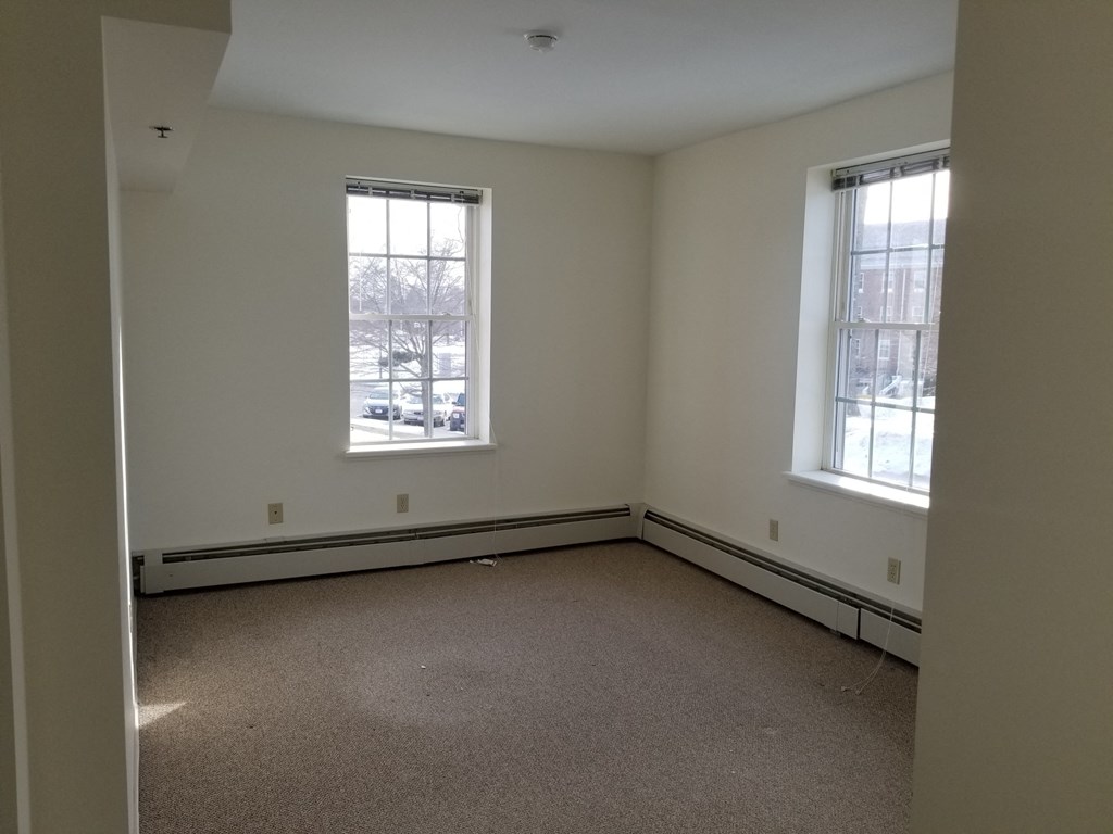 an empty room with two windows and a carpeted floor