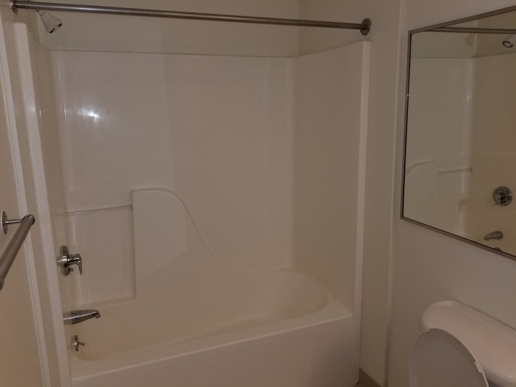 a small white bathroom with a shower and a toilet