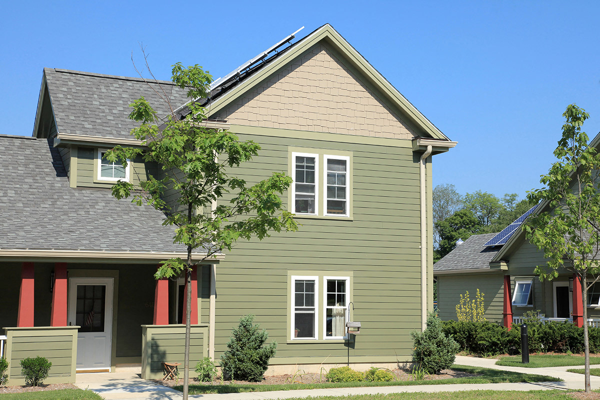 a green house with a gray roof and red doors