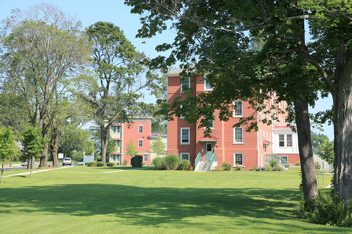 a large red brick building with a green lawn and trees