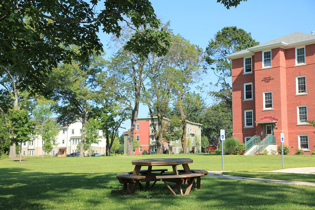 a picnic table in a park in front of a brick building