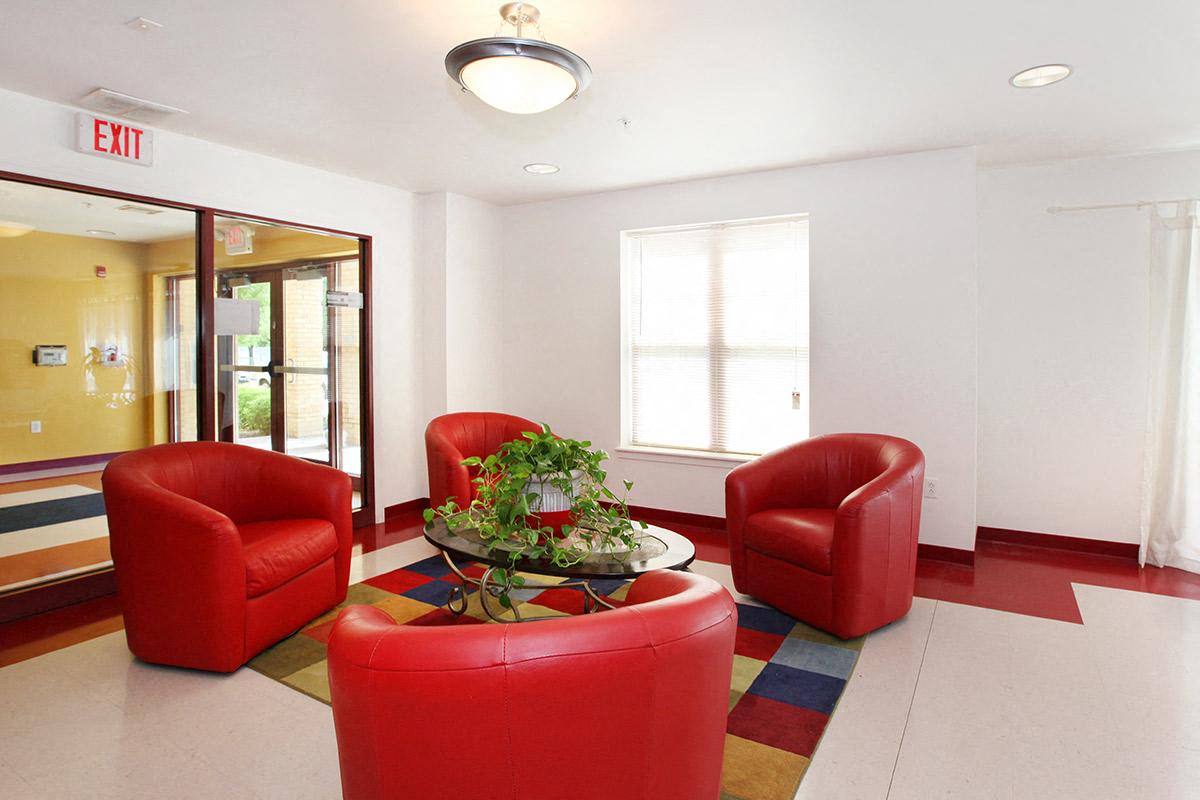 a lobby with red chairs and a table with a plant
