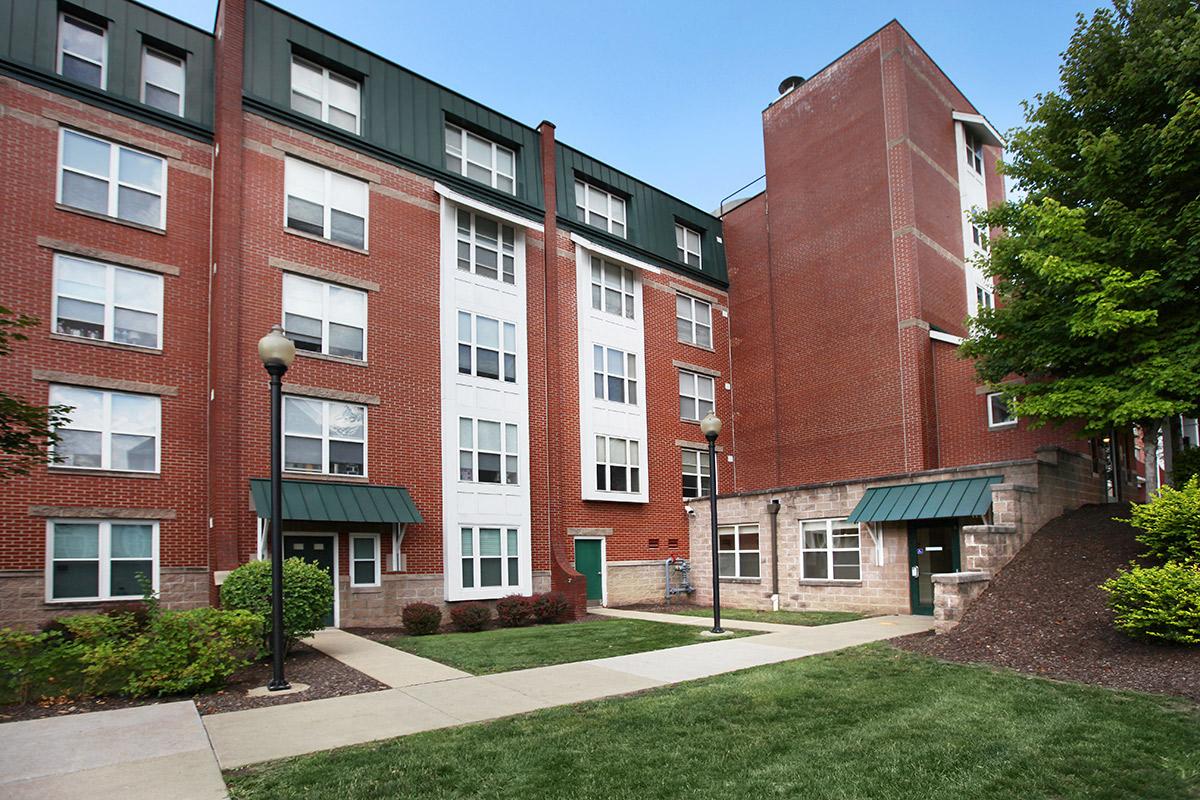 an exterior view of a brick building with green grass and a sidewalk