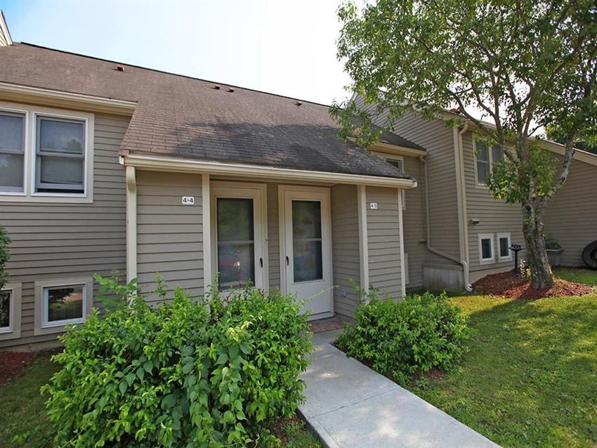 a small gray house with a sidewalk in front of it