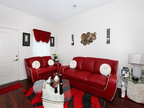 a living room with two red couches and a glass table