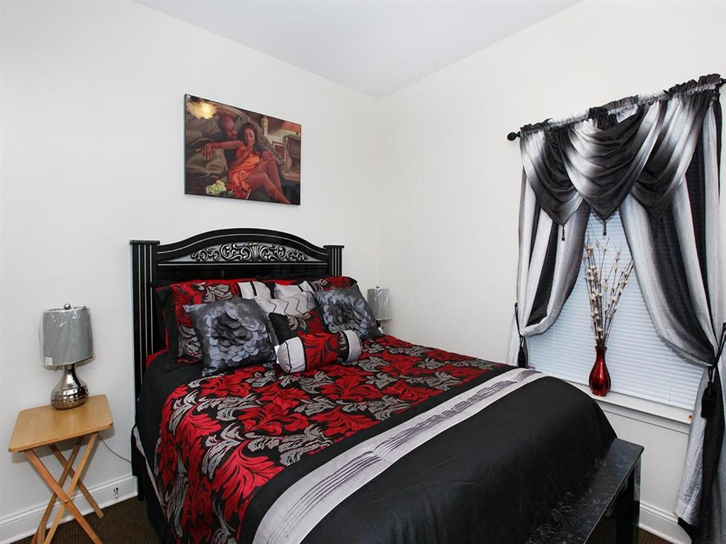 a bedroom with a bed and curtains and a painting on the wall