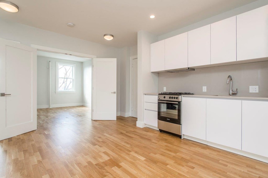 an empty kitchen with white cabinets and a wood floor