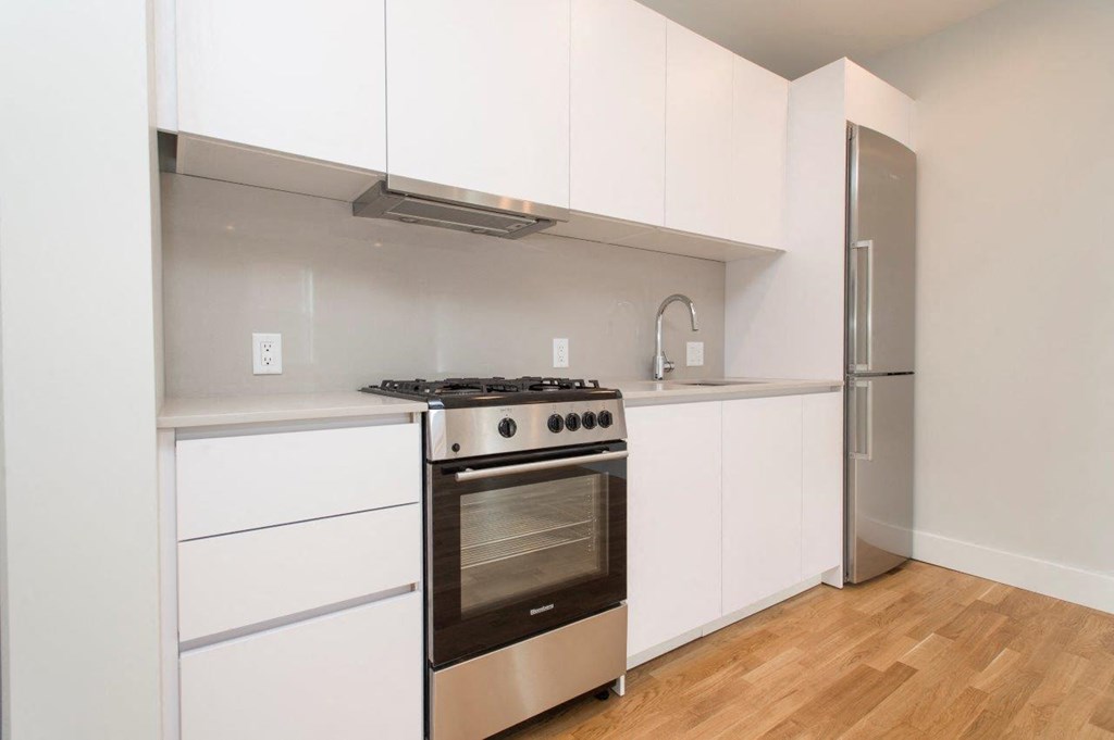a kitchen with white cabinets and a stove and a refrigerator