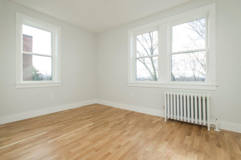 an empty room with a wood floor and two windows