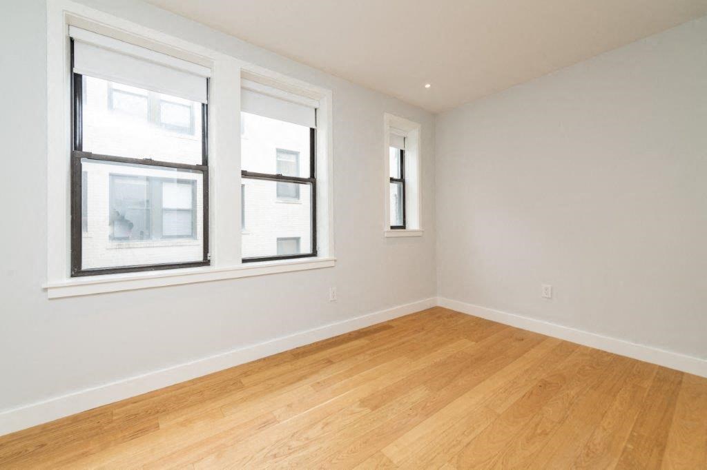 an empty room with two windows and a wooden floor