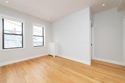an empty living room with a wooden floor and two windows