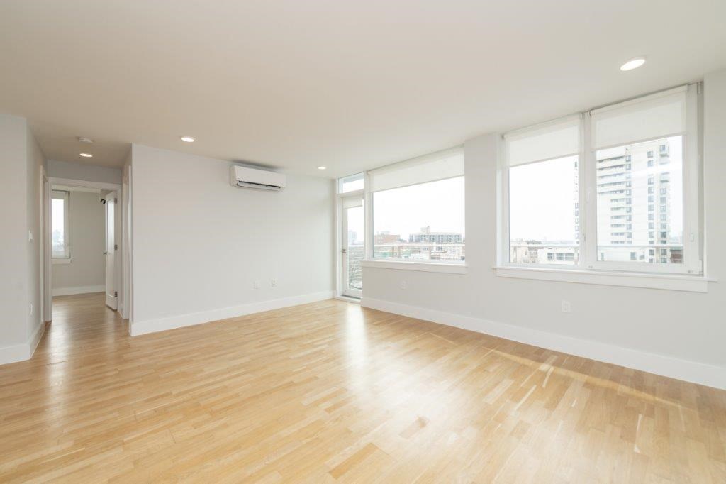 an empty living room with a wood floor and large windows