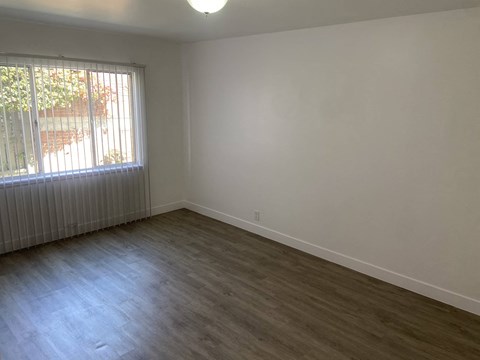 an empty living room with a window and wooden floors