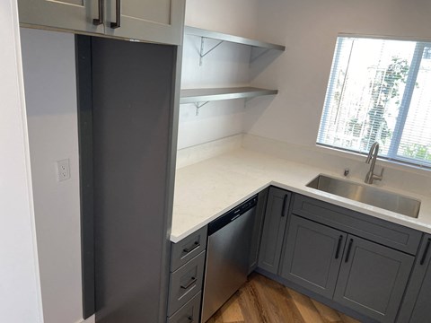 a kitchen with gray cabinets and a sink and a window