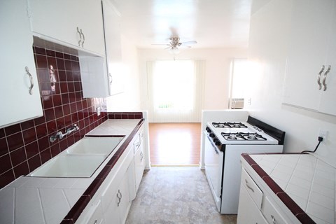 an empty kitchen with white cabinets and a stove