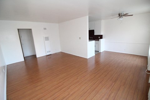 an empty living room with wood flooring and a ceiling fan