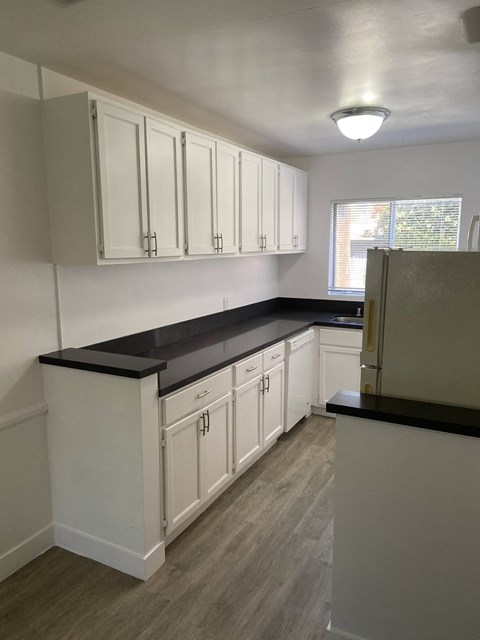 a kitchen with white cabinets and black counter tops