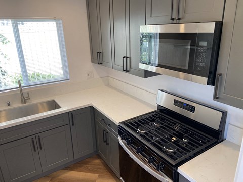 a kitchen with gray cabinets and a stove and a microwave